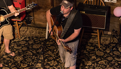 Guitarist playing in front of an amp on a chair.