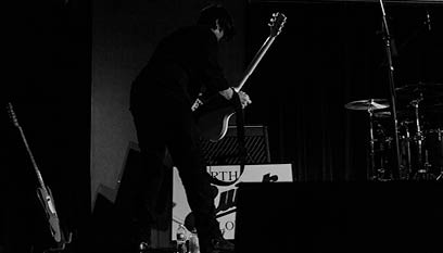 Guitarist holding guitar in front of an amp (on an amp stand)