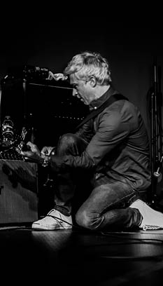 Guitarist kneeling on the floor to get feedback