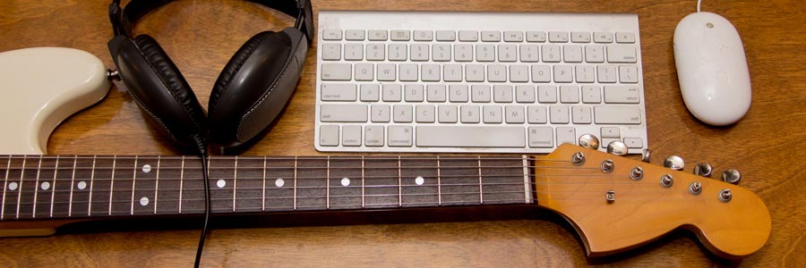 A keyboard, headphones, a computer mouse, and a guitar neck